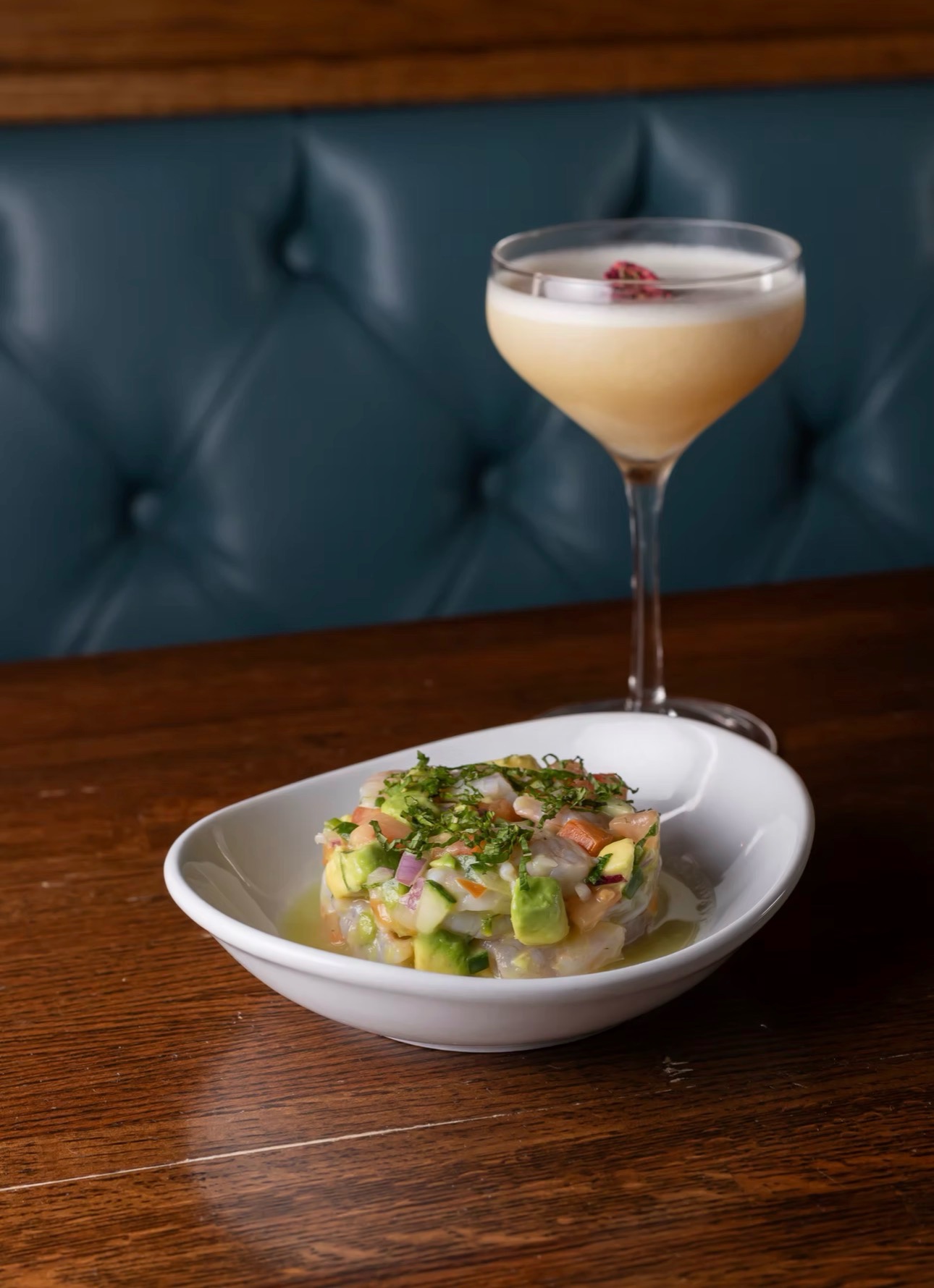 Shrimp & avocado ceviche alongside a foamy coupe cocktail garnished with a dried rose.